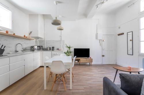 une cuisine avec des armoires blanches et une table et des chaises dans l'établissement Charmant T2, centre ville, lumineux, à Aix-en-Provence