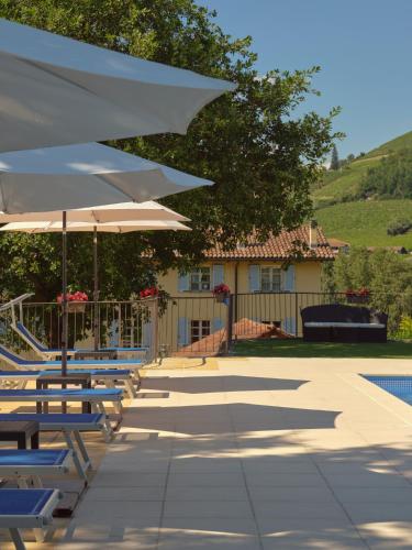 a row of chairs and umbrellas next to a pool at Vigna Dell'Acqua in Santo Stefano Belbo