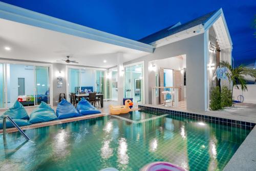 a swimming pool with blue pillows in a house at พลอยพูลวิลล่า ชะอำ 4 Ploy Poolvilla Cha-am 4 in Cha Am