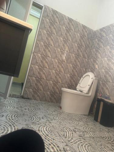 a bathroom with a toilet and a tiled wall at Avina specious room in Lomé
