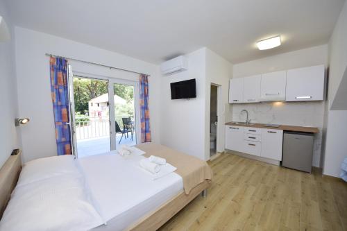 a bedroom with a large bed and a kitchen at Holiday Resort Balota in Viganj