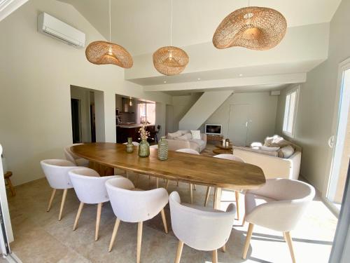 ルオムにあるMaison pour 12p, piscine à débordement chauffée d'avril à octobre inclusの木製のテーブルと白い椅子のあるダイニングルーム