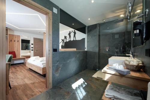 a bathroom with a tub and a sink and a mirror at Dolomiten Hotel Irma in Canazei