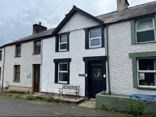 una casa bianca con una panchina davanti di The Cosy Cottage a Llanberis