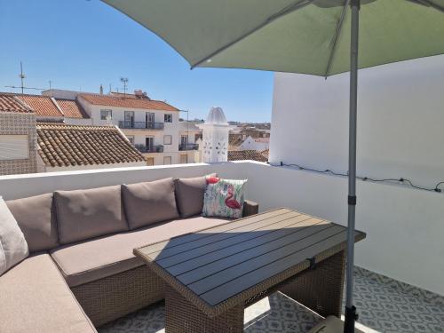 a couch and an umbrella on a balcony at House with Private Roof Terrace in Centre in Tavira