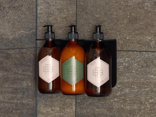 three bottles of soap sitting on a tile floor at Boudoir des Muses in Paris