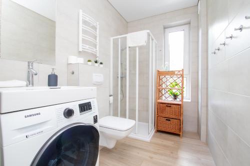 a bathroom with a toilet and a washing machine at Sunny Pines Apartment in Palanga