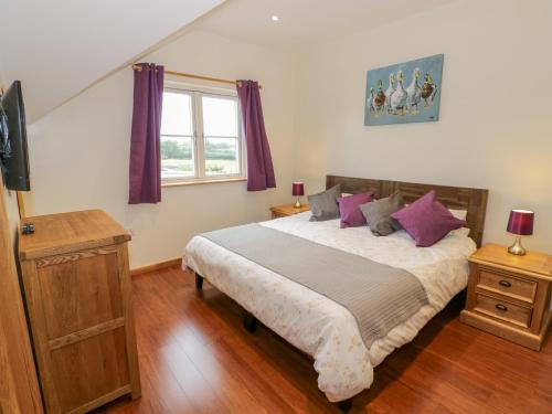 ein Schlafzimmer mit einem Bett mit lila Kissen und einem Fenster in der Unterkunft Lavender Cottage in Warwick