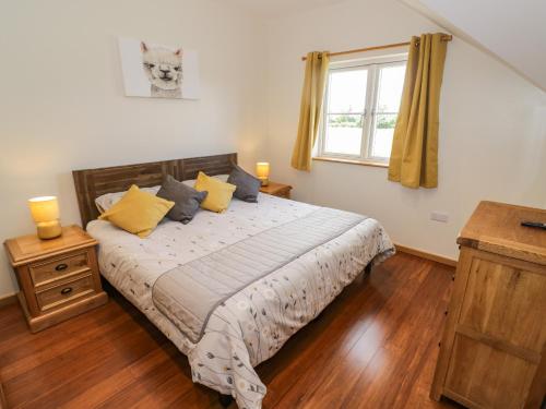 ein Schlafzimmer mit einem Bett mit gelben Kissen und einem Fenster in der Unterkunft Daisy Cottage in Warwick