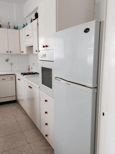 a white kitchen with white cabinets and a refrigerator at Erini Villa in Protaras