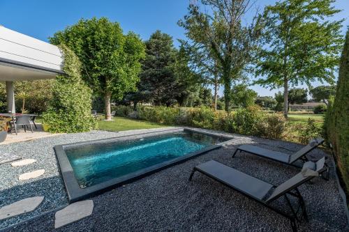 une piscine avec deux chaises longues à côté dans l'établissement 1ère ligne sur le golf piscine, clim, barbecue, à Baillargues