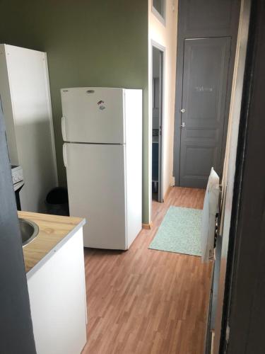 une cuisine avec un réfrigérateur blanc à côté d'une porte dans l'établissement Appartement proche de la mer, à Dunkerque