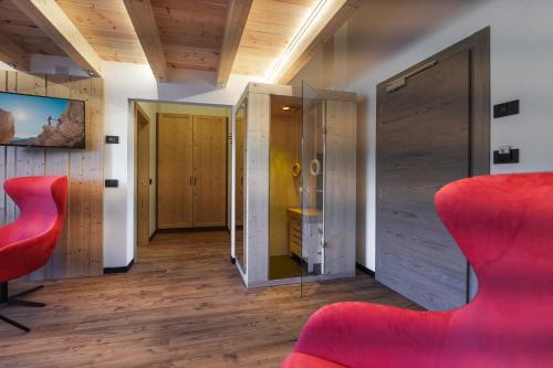 a room with a red chair and a mirror at Dolomiten Hotel Irma in Canazei