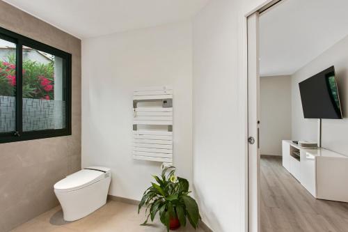 La salle de bains blanche est pourvue de toilettes et d'une télévision. dans l'établissement 1ère ligne sur le golf piscine, clim, barbecue, à Baillargues