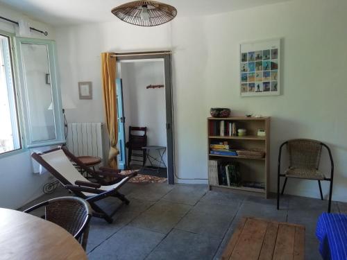 un salon avec des chaises, une table et une étagère dans l'établissement Chez Pauline, à Murviel-lès-Montpellier