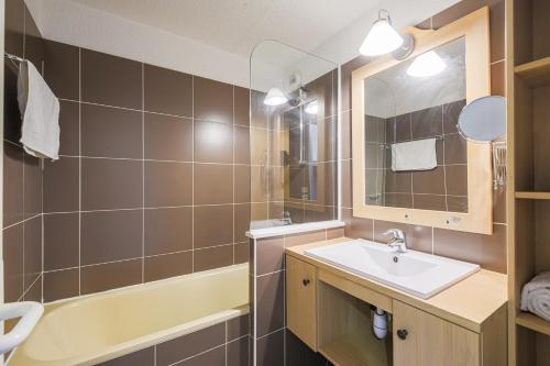 ein Badezimmer mit Waschbecken, Badewanne und Spiegel in der Unterkunft Le Berger - Apt dans résidence 4 étoiles au pied des pistes in Huez
