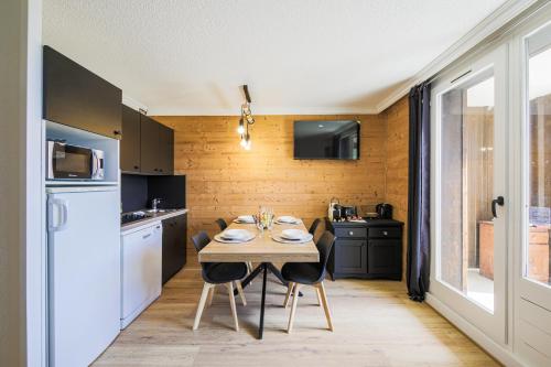 une cuisine avec une table avec des chaises et un réfrigérateur dans l'établissement Le Berger - Apt dans résidence 4 étoiles au pied des pistes, à Huez