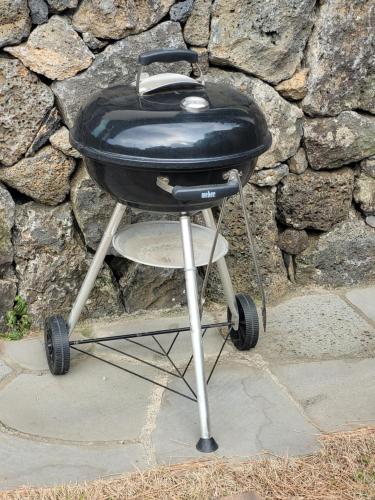a black grill sitting on top of a stone wall at Joohane Jejudo House in Jeju