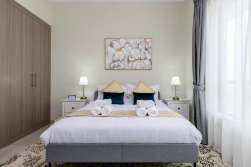 a bedroom with a large bed with towels on it at Waves - Stylish 1BR Close to IMG World & Global Village in Dubai
