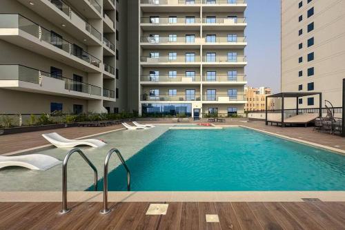 a swimming pool in front of a building at Waves - Stylish 1BR Close to IMG World & Global Village in Dubai