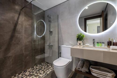 a bathroom with a toilet and a shower and a mirror at Waves - Stylish 1BR Close to IMG World & Global Village in Dubai
