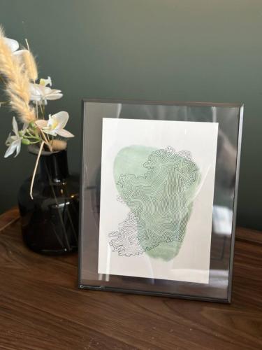 a picture in a glass box on a table with flowers at The Lookout Barn by Mourne Homestays in Brackenagh
