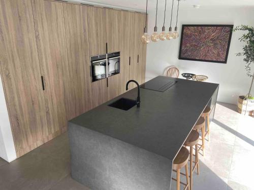a kitchen with a black counter top and wooden cabinets at The Lookout Barn by Mourne Homestays in Brackenagh