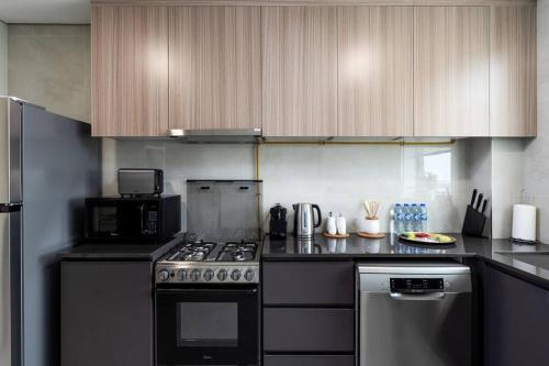 a kitchen with a stove and a microwave at Waves - Stylish 1BR Close to IMG World & Global Village in Dubai