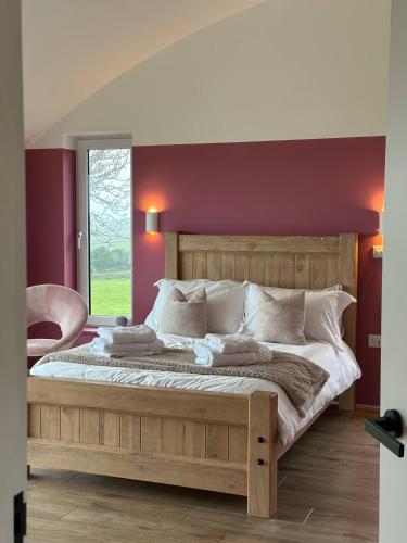 a bedroom with a large wooden bed with a red wall at The Lookout Barn by Mourne Homestays in Brackenagh