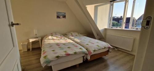 a small bed in a small room with a window at Der Springbrunnen in Egmond aan Zee