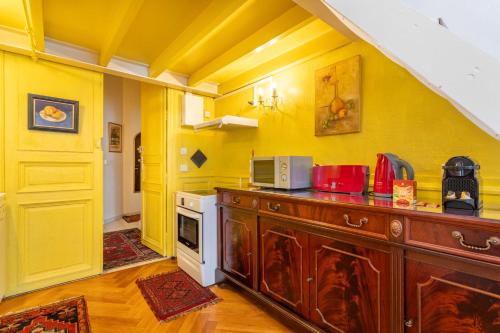 une cuisine avec des murs jaunes et un comptoir avec un four micro-ondes dans l'établissement 1 bedroom duplex with AC near the Old Port, à Marseille