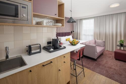 a kitchen with a counter with a microwave and a living room at Hyatt House Paris Charles de Gaulle Airport in Roissy-en-France