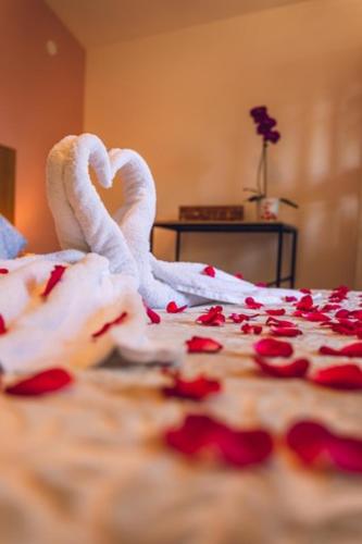 a bed with white towels and red rose pedals at Le Palmier de la Paix in Le Tampon