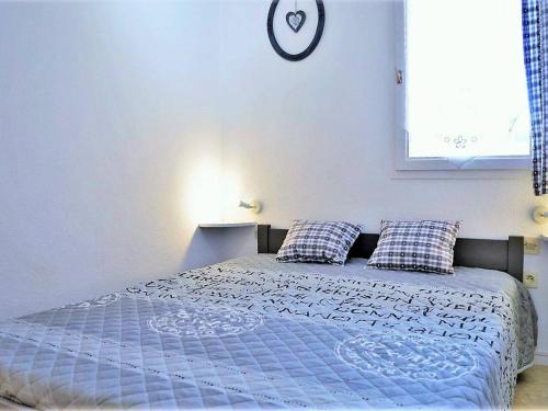 un lit dans une chambre avec une horloge au mur dans l'établissement Appartement 4 couchages à 350m de la plage avec garage privatif à Bormes-les-Mimosas - FR-1-251-725, à Bormes-les-Mimosas