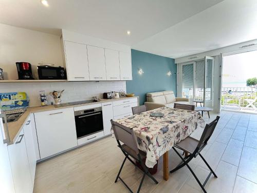 une cuisine avec une table et des chaises et une cuisine avec des armoires blanches dans l'établissement Appartement rénové face mer avec terrasse, 2 pièces, 3 couchages à La Baule - FR-1-245-193, à La Baule