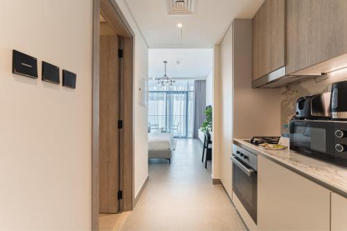 a kitchen with a hallway leading to a living room at HAVN - Smart Home Studio in Oxford Terraces, JVC in Dubai