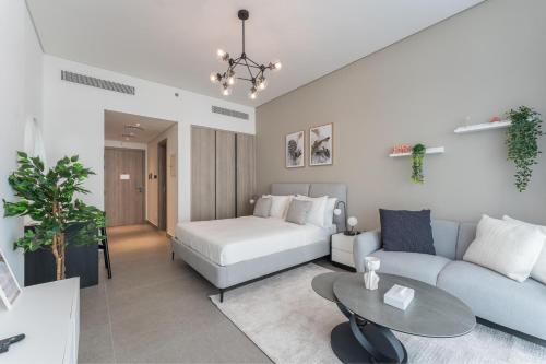 a living room with a couch and a bed at HAVN - Smart Home Studio in Oxford Terraces, JVC in Dubai