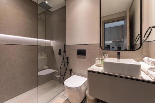 a bathroom with a toilet and a sink and a mirror at HAVN - Smart Home Studio in Oxford Terraces, JVC in Dubai