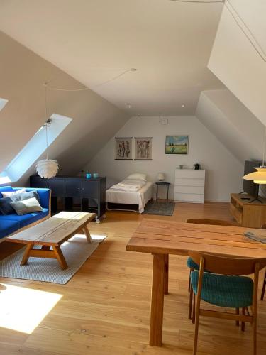 a attic living room with a bed and a table at Strandsegård Ferielejlighed in Ølsted