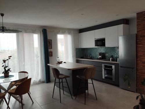 une cuisine avec un comptoir, une table et des chaises dans l'établissement T2 vue Pyrénées au Sud de Toulouse, à Toulouse
