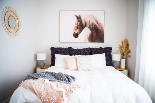 a bedroom with a bed with a picture of a horse at Rustling Oaks NZ Boho Pool House in Cambridge