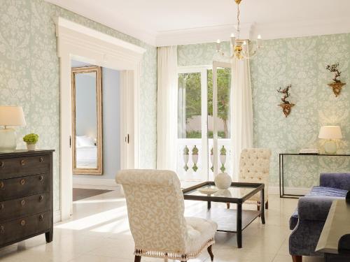a living room with a table and a chair at Mandola Rosa at Riviera Olympia, A Grecotel Resort to Live in Loutra Killinis