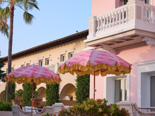 two umbrellas in front of a building at Mandola Rosa at Riviera Olympia, A Grecotel Resort to Live in Loutra Killinis