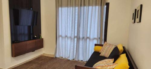 a living room with a couch and a television at Apto próximo Ribeirão Shopping in Ribeirão Preto