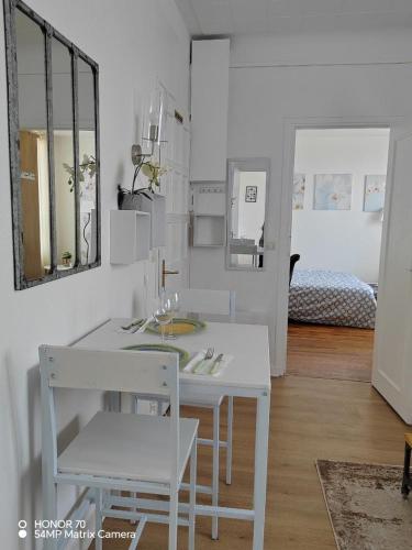 une salle à manger blanche avec une table et deux chaises dans l'établissement Charmant appartement - Gare SNCF-RER et sites JO 2024, à Saint-Cyr-lʼÉcole