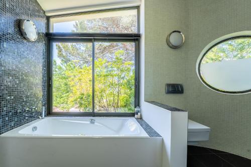 une salle de bain avec une grande baignoire et une fenêtre dans l'établissement Mont Saint-Clair vue mer et étang, piscine et Clim, à Sète
