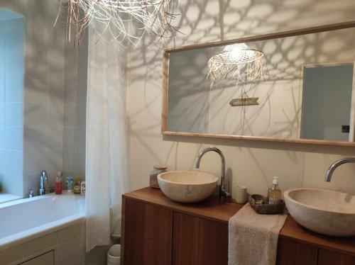 une salle de bain avec deux lavabos, un miroir et une baignoire dans l'établissement L' Authentique - Longère de caractère rénovée, à Vault-de-Lugny