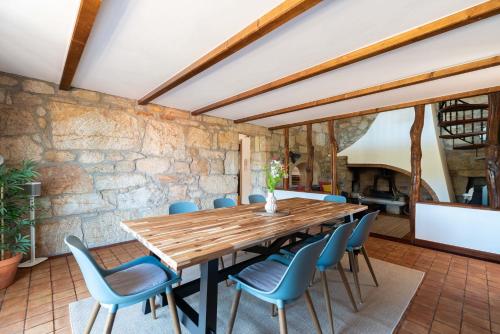 a dining room with a wooden table and blue chairs at Casona Playa By Limens in Hio