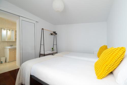a bedroom with a white bed with a yellow pillow at Casona Playa By Limens in Hio