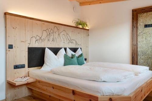 a bedroom with a large white bed with a wooden headboard at Moserhof Wohnung Salbei in Meltina